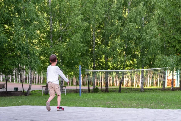 The boy runs in the park. child on stage. basketball net in the park