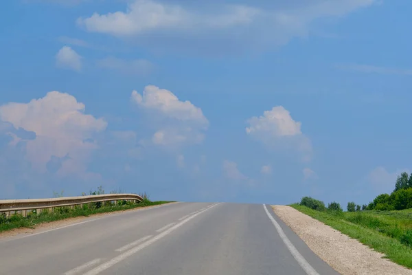 Road to sky.  Highway through the fields.  Clouds over the road