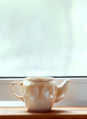 Masada bir fincan çay. Pencere kenarındaki çaydanlık