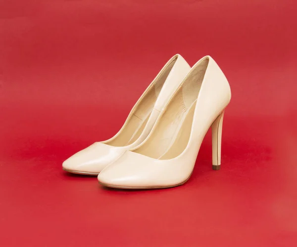 Beige high heel shoes isolated on the red background