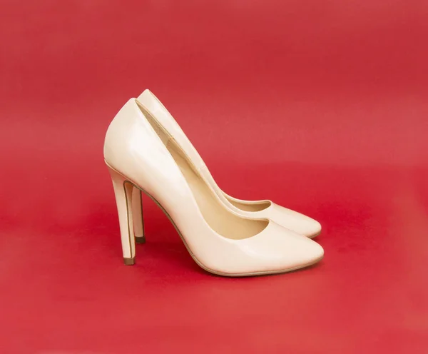 Beige high heel shoes isolated on the red background