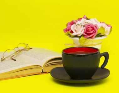 Sıcak çay ve kitap sarı zemin üzerine siyah Kupası