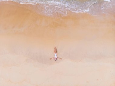 Kumlu sahilde bikinili genç güzel kadın sunbathes