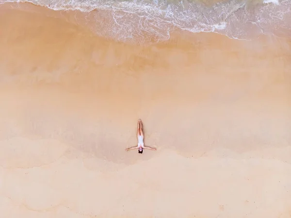 La giovane bella donna in bikini prende il sole sulla spiaggia sabbiosa Fotografia Stock