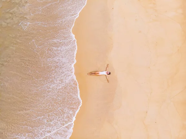 La giovane bella donna in bikini prende il sole sulla spiaggia sabbiosa Immagine Stock