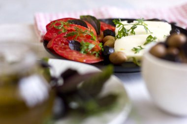 Beyaz peynir domates, yeşil ve siyah zeytin, fesleğen, kişniş ve zeytinyağı siyah plaka üzerinde