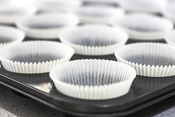 Empty paper forms for muffins and cupcakes in a metal tray