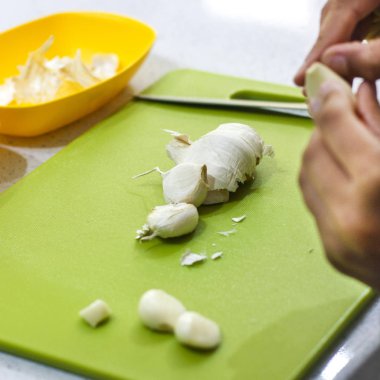 Eller taze sarımsak mutfakta yeşil kartı üzerindeki kesme