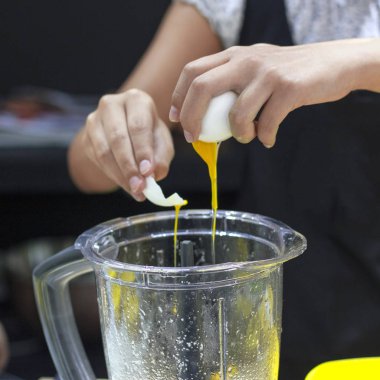 Aşçı blender içine çiğ yumurta kırar. Yumurta sarısı akan.