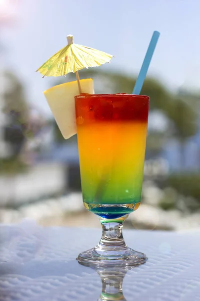 Bright cocktail with umbrella on background of the pool