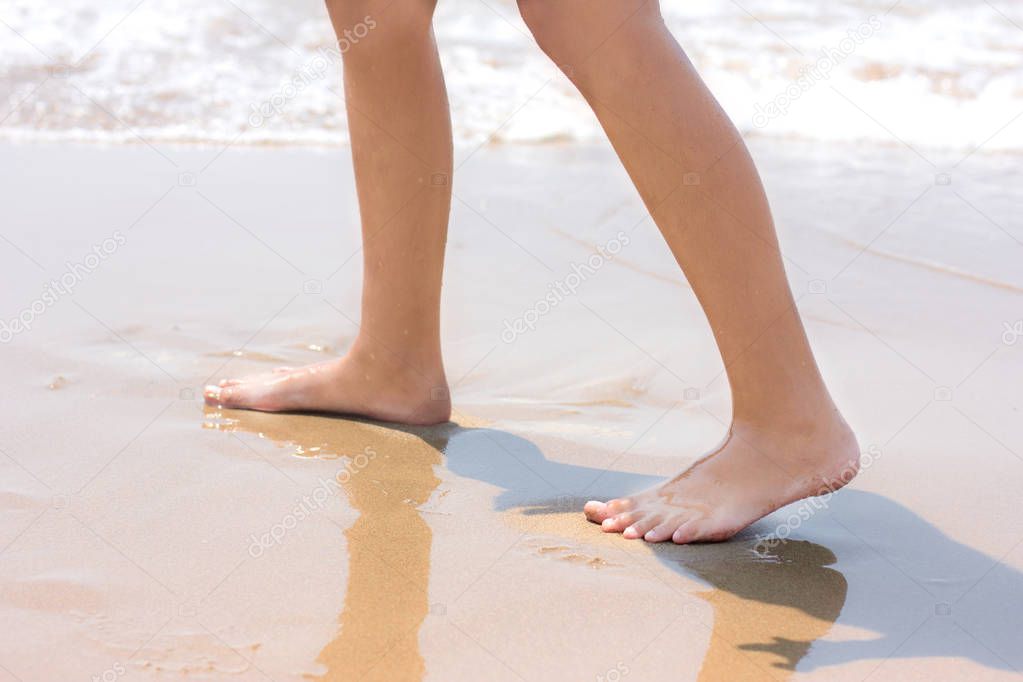 Bare feet walking at sandy beach near by sea