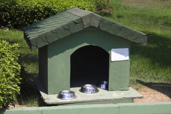 Cottage for cats with bowls for feed on a green lawn