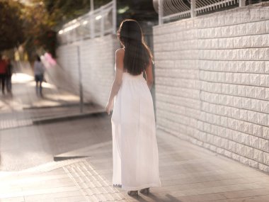 Beyaz elbiseli güzel esmer kız sokakta standı