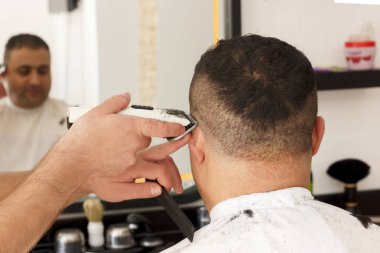 Arkadan görünüşü erkek kısa saç kesme kuaför dükkanında bir kesme makinesi makine ile almak.