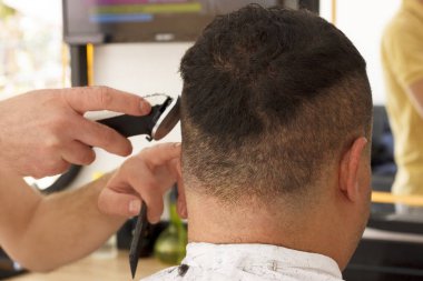 Arkadan görünüşü erkek kısa saç kesme kuaför dükkanında bir kesme makinesi makine ile almak.