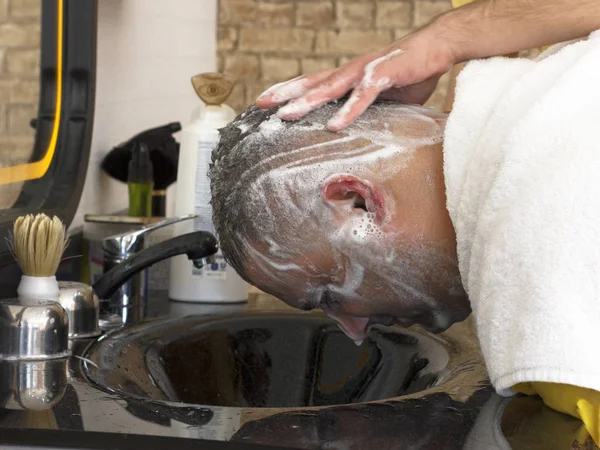 Hairdresser washing hair to turkish man after haircut in barber shop