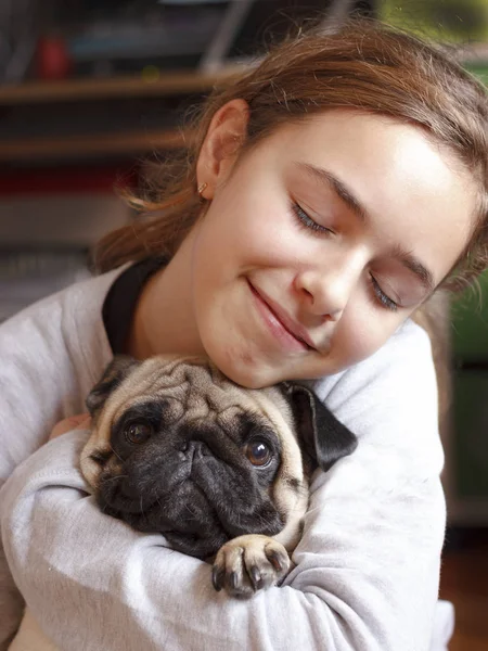Счастливая Улыбающаяся Девочка Подросток Обнимает Милую Собачку Мопса Любовью — стоковое фото
