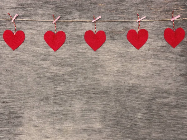 Red Valentine's love hearts on natural cord and pink pins hanging on rustic texture background, copy space