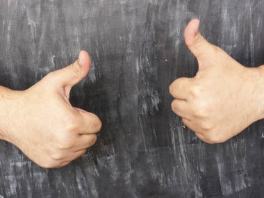 Adam başparmak kara tahta arka plan karşı gösterir