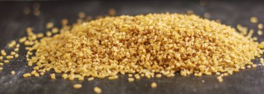 Siyah ahşap bir masa üzerinde ham bulgur yığını