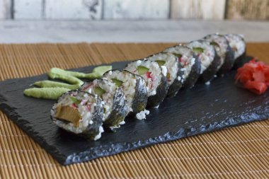 Japon wasabi ve zencefil ile kara tahta üzerinde salatalık, yengeçler ve omlet ile rulo