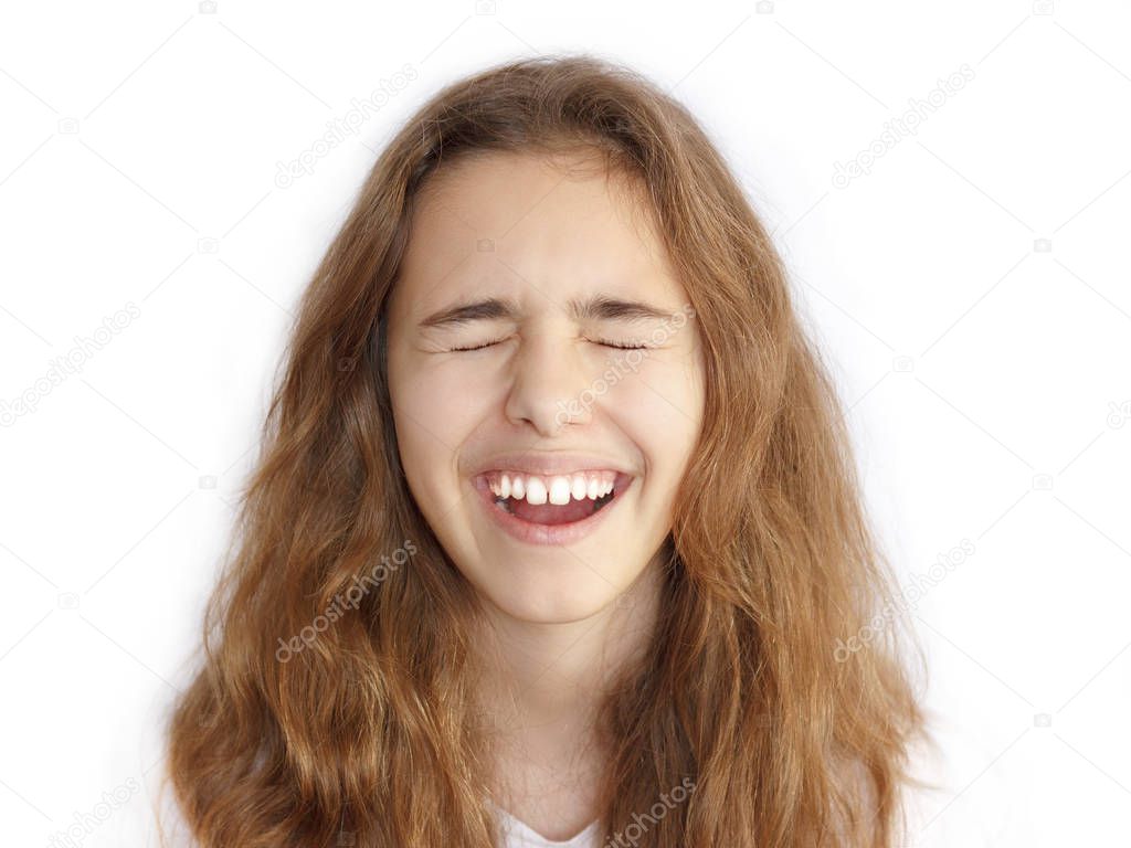 Pretty teenager girl with long hair makes very funny face and laughing with the closed eyes