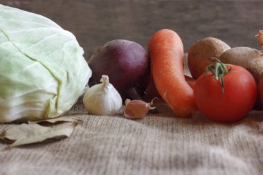 Pancar çorbası borsch için çiğ sebze. Beyaz lahana, pancar, havuç, patates, domates, sarımsak ahşap tahta üzerinde