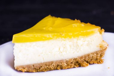 Limonlu cheesecake siyah bir zemin üzerine limon lezzet yakın çekim ile dekore edilmiştir.