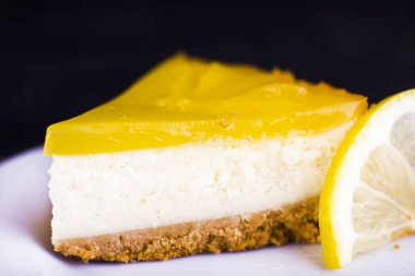 Limonlu cheesecake siyah bir zemin üzerine limon lezzet yakın çekim ile dekore edilmiştir.