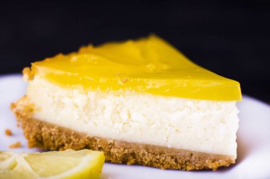 Limonlu cheesecake siyah bir zemin üzerine limon lezzet yakın çekim ile dekore edilmiştir.