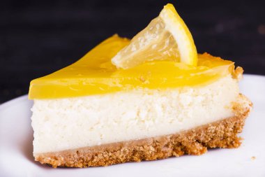 Limonlu cheesecake siyah bir zemin üzerine limon lezzet yakın çekim ile dekore edilmiştir.