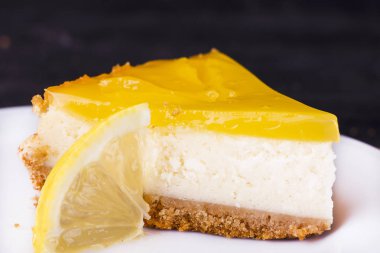 Limonlu cheesecake siyah bir zemin üzerine limon lezzet yakın çekim ile dekore edilmiştir.
