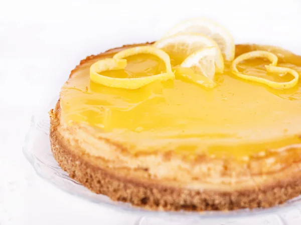 レモンの皮のクローズ アップで飾られた白地にレモン チーズケーキ — ストック写真