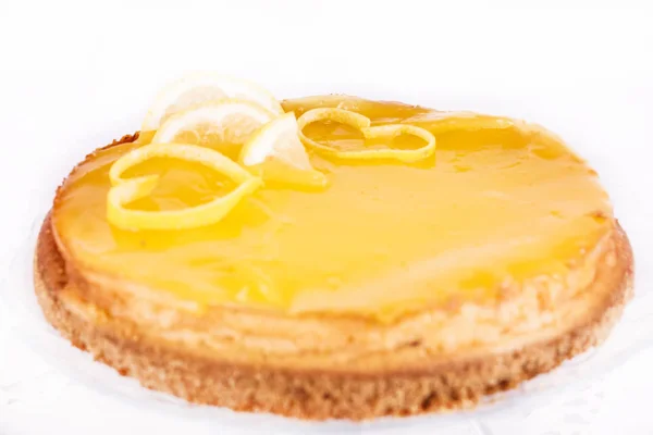 Lemon cheesecake on a white background decorated with lemon zest close-up