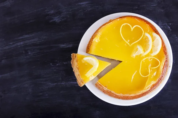 Lemon cheesecake on a black background decorated with lemon zest close-up