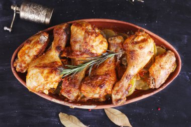 Çanak çömlek fırında pişmiş kırmızı biber soslu tavuk. Tavuk budu ve kanatlar