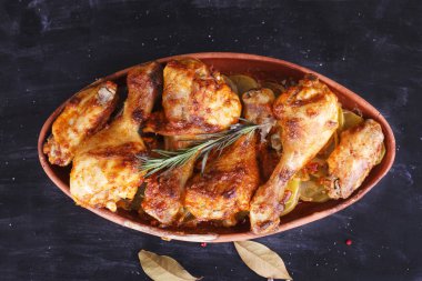 Çanak çömlek fırında pişmiş kırmızı biber soslu tavuk. Tavuk budu ve kanatlar