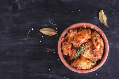 Çanak çömlek fırında pişmiş kırmızı biber soslu tavuk. Tavuk budu ve kanatlar