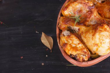 Çanak çömlek fırında pişmiş kırmızı biber soslu tavuk. Tavuk budu ve kanatlar