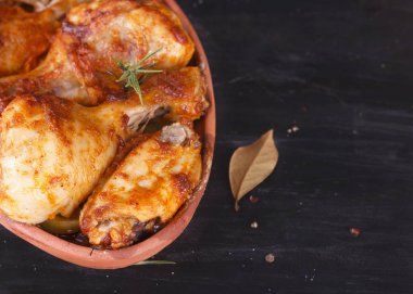 Çanak çömlek fırında pişmiş kırmızı biber soslu tavuk. Tavuk budu ve kanatlar