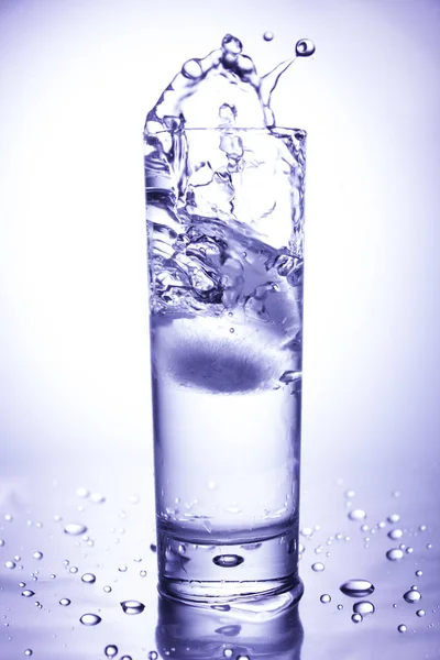 エコロジーコンセプト。きれいな水のガラスに投げ込まれた氷からスプラッシュ — ストック写真