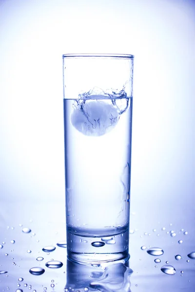 エコロジーコンセプト。きれいな水のガラスに投げ込まれた氷からスプラッシュ — ストック写真
