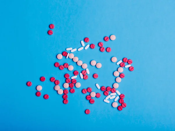 Multicolored medical pills and drugs on blue background — Stock Photo, Image