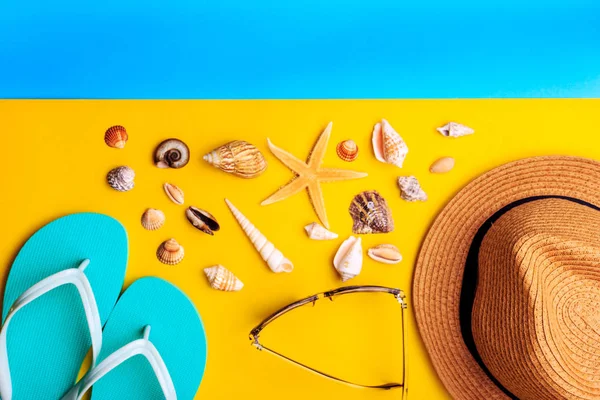 Muscheln und Sterne. Strohhut und Minzpantoffeln auf gelbem und blauem Hintergrund. — Stockfoto