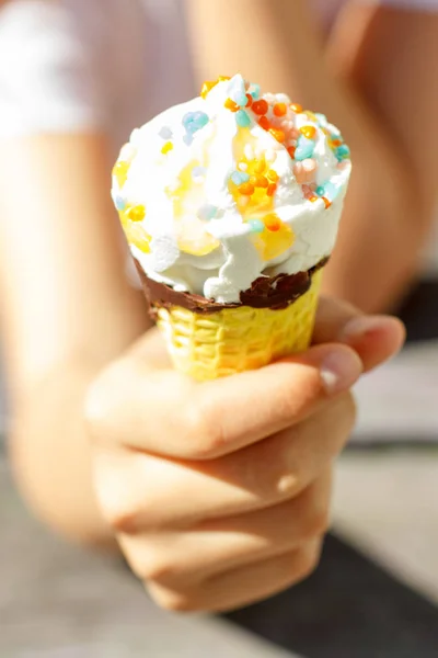 Рука держит мороженое в вафельном конусе летом под солнцем. Селективный фокус — стоковое фото