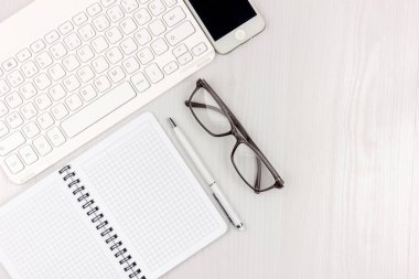 Dizüstü bilgisayar, akıllı telefon, gözlük, dizüstü bilgisayar ve kopya alanı arka plan ile kalem ile beyaz ofis masası düz yatıyordu. Mockup