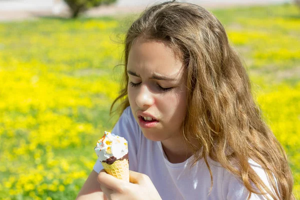 Недовольная несчастная девочка-подросток летом ест безвкусное мороженое в вафельном рожке. Селективный фокус — стоковое фото