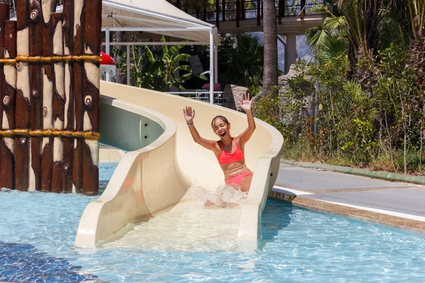 Alegre riendo adolescente chica va abajo por tobogán de agua en el hotel aquapark — Foto de Stock