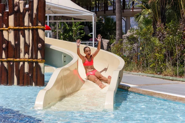 Neşeli gülen genç kız otel aquapark su kaydırağı tarafından aşağı iner