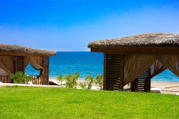 Paviljong med halmtak på en sandstrand. Medelhavet sommar-och havs — Stockfoto